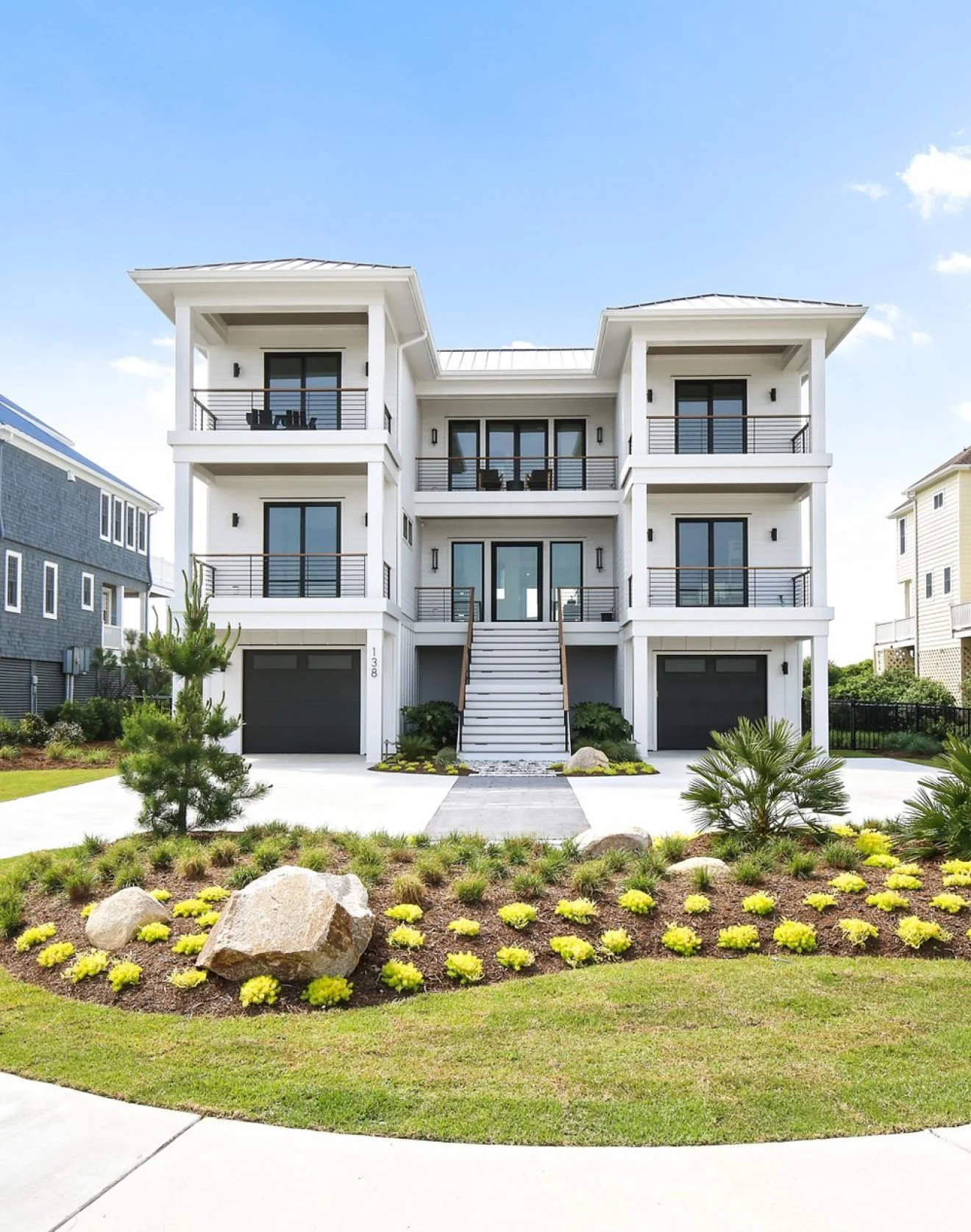 Three-storey coastal new-build home with white siding, black windows and a standing-seam metal roof